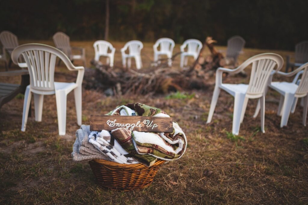 A basket of folded blankets beside chairs set around an outdoor fire pit